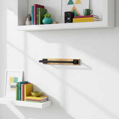 Oak and black wall shelf styled with colorful books, art, plant, speaker, and ceramics